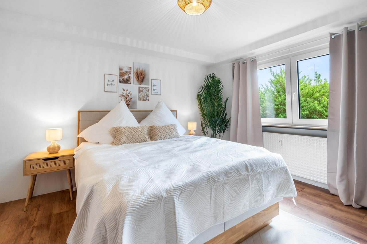 Zweites Schlafzimmer mit Holzbett und Vorhängen