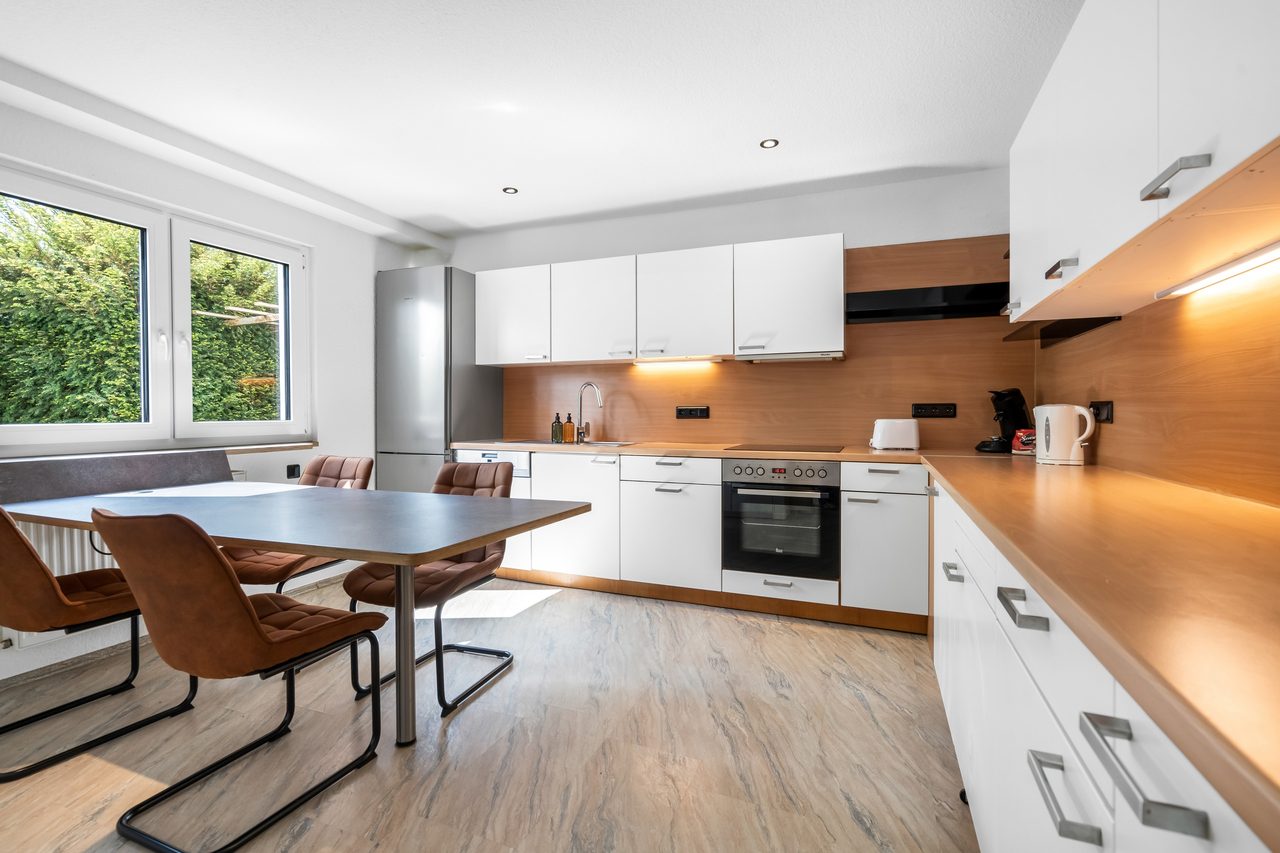 Ferienwohnung Edersee, helle offene Wohnküche mit Essplatz und Fenstern ins Grüne