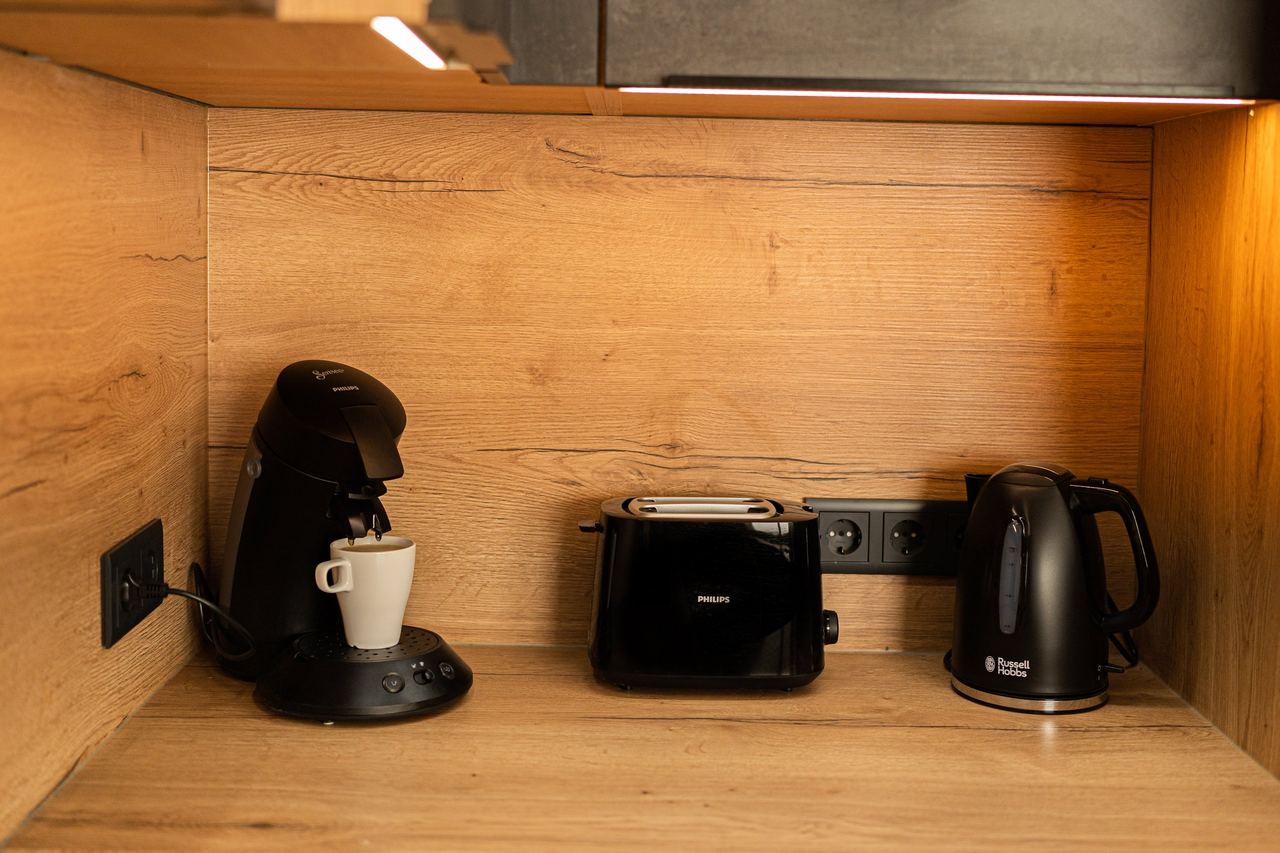 Küchenecke mit Kaffeepadmaschine, Toaster und Wasserkocher auf Holzarbeitsplatte