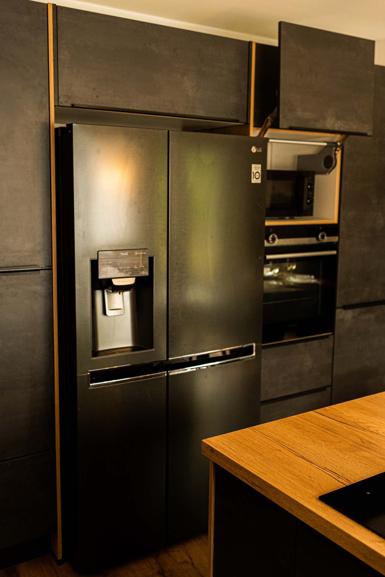 Küche mit schwarzem Side-by-Side-Kühlschrank und eingebautem Backofen
