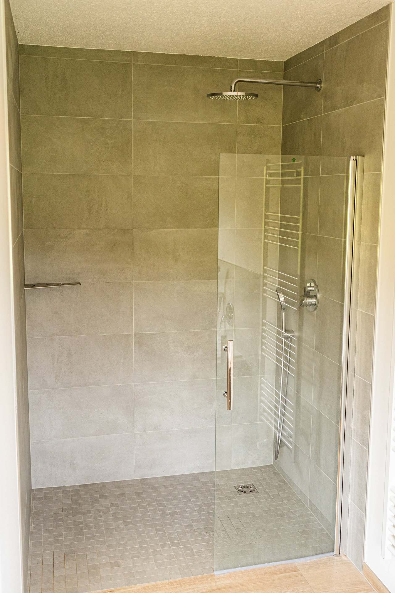 Badezimmer mit ebenerdiger Dusche, Glaswand und grauen Fliesen