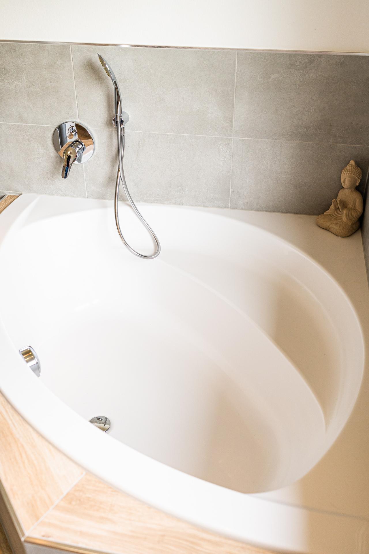 Badezimmer mit weißer Eckbadewanne und Handbrause