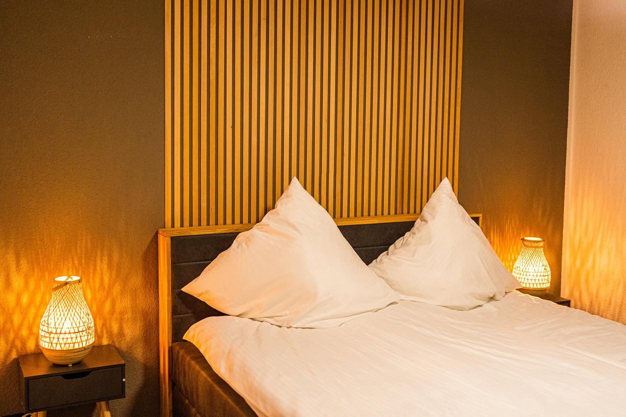 Schlafzimmer mit Doppelbett, weißer Bettwäsche und zwei Nachttischlampen