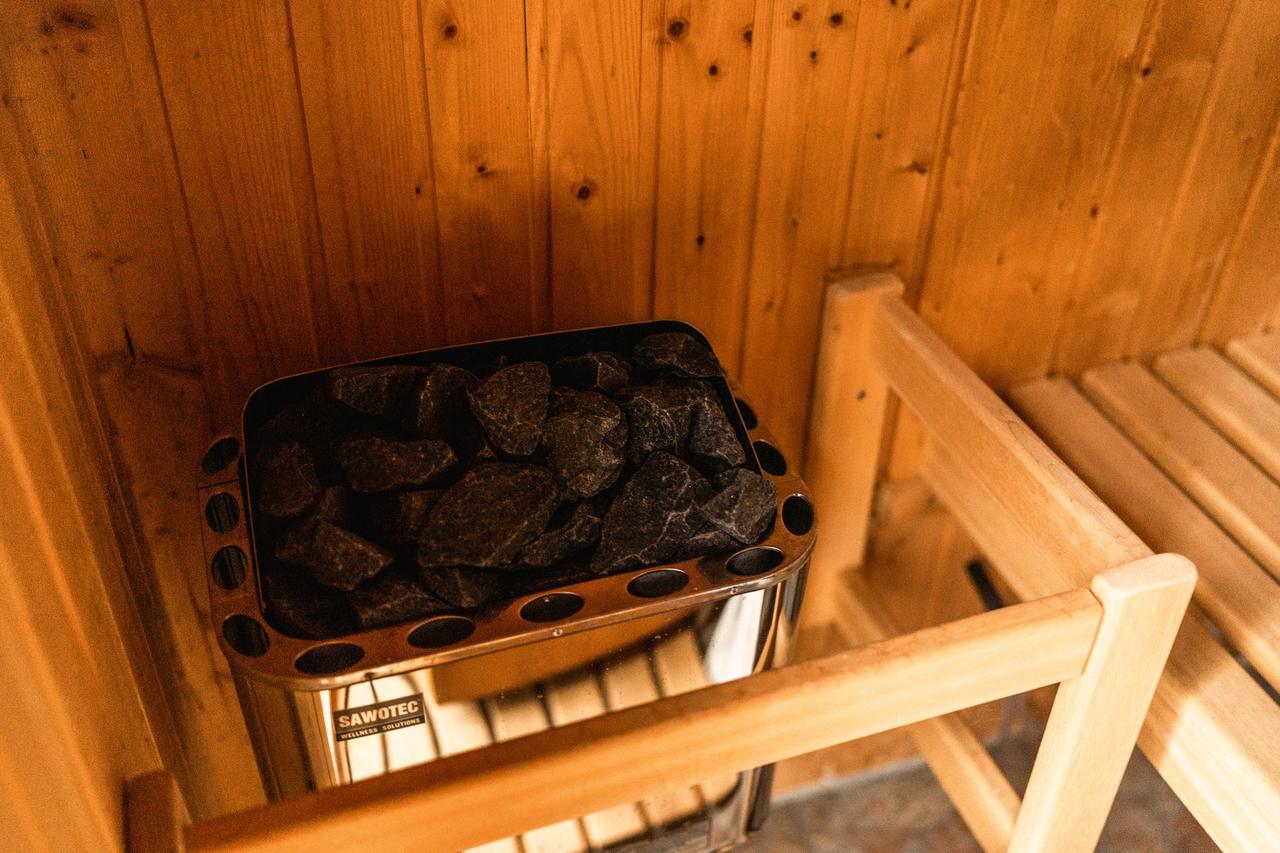 Sauna mit Holzbänken und Saunaofen mit Steinen