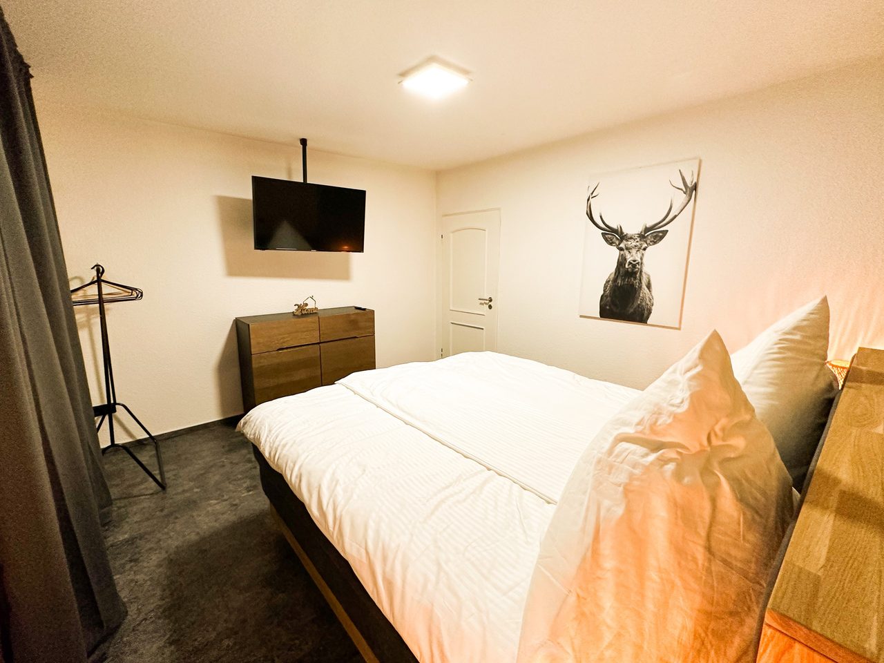 Schlafzimmer mit Doppelbett, Wandfernseher und Hirschbild