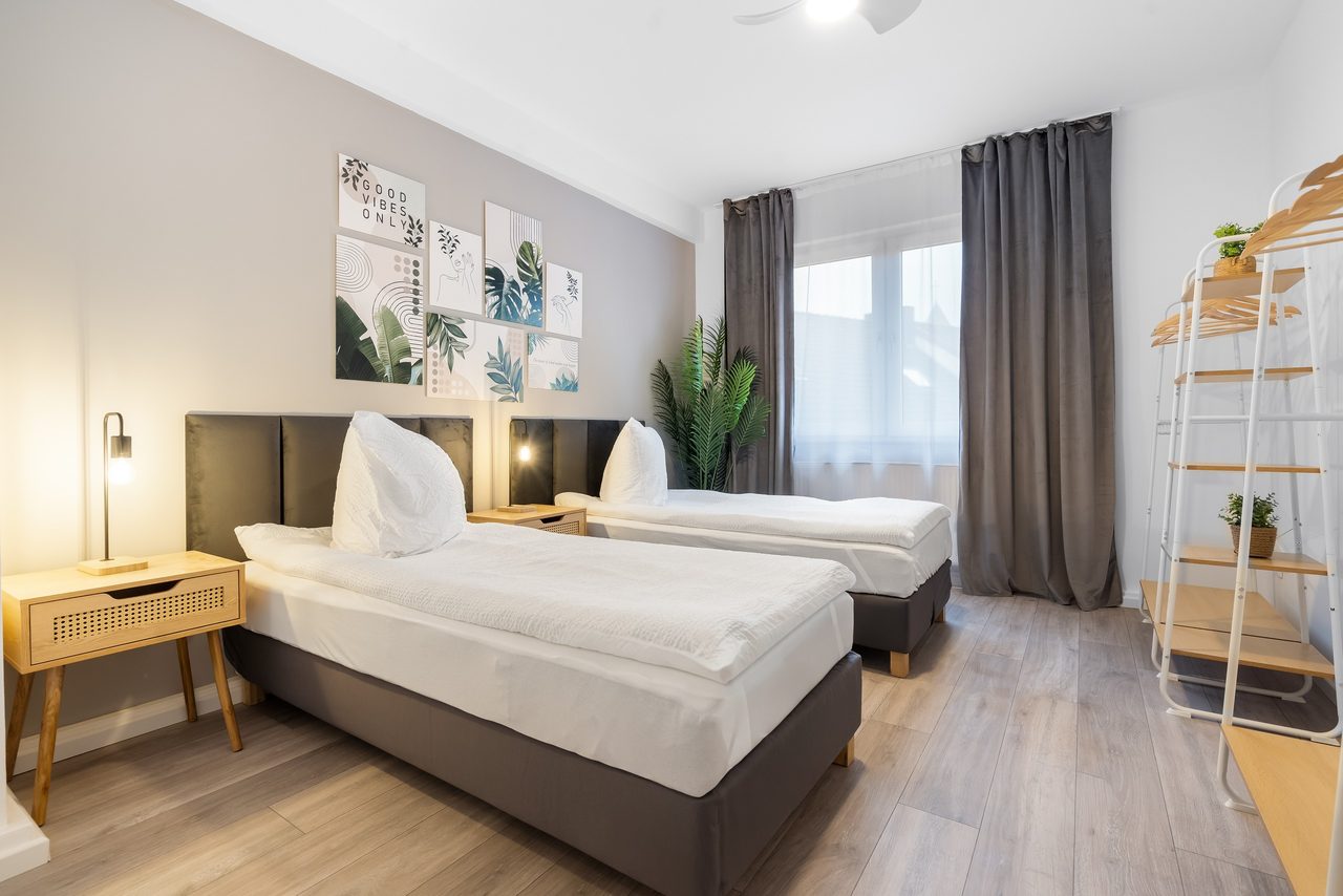 Schlafzimmer mit zwei Einzelbetten, Bilderwand und Kleiderregal