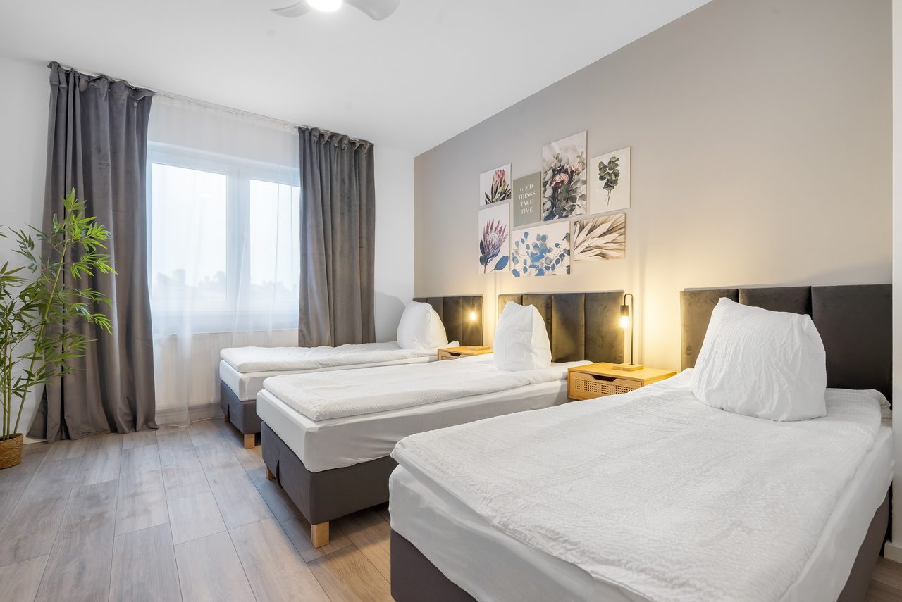 Schlafzimmer mit drei Einzelbetten, Bilderwand und grauen Vorhängen