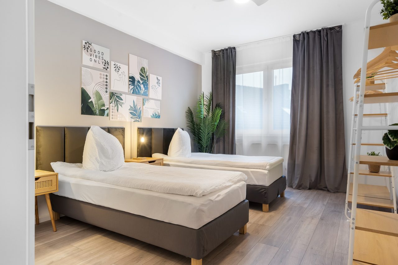 Schlafzimmer mit zwei Einzelbetten, Pflanzenbildern und Kleiderregal