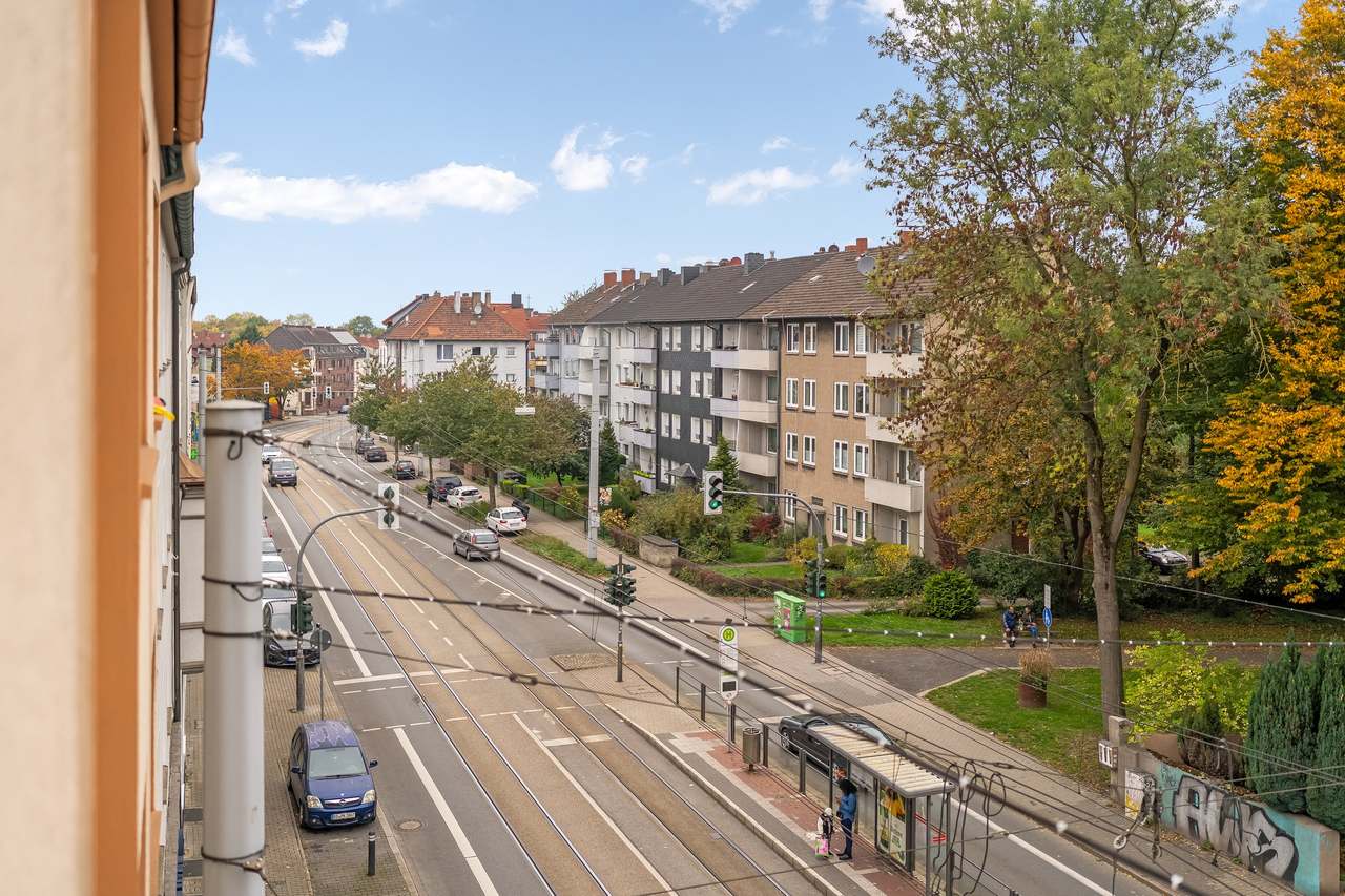 Blick auf eine Straße mit Straßenbahnschienen und Wohnhäusern