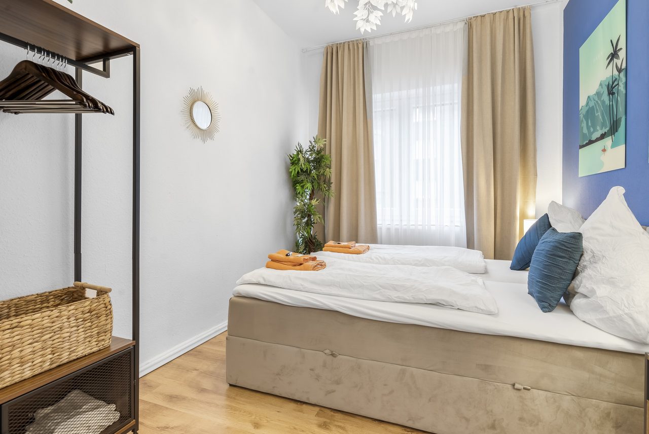 Schlafzimmer mit Doppelbett, Kleiderständer mit Korb und Sonnenspiegel