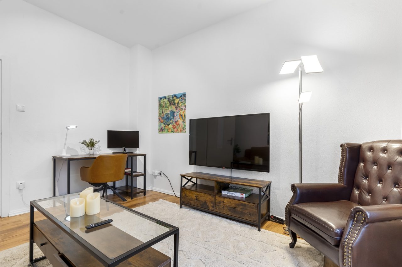 Wohnzimmer mit Fernseher, Chesterfield Sessel und kleinem Schreibtisch