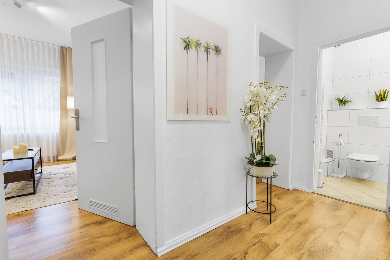 Flur mit Orchidee, Palmenbild und Blick ins Wohnzimmer und Bad