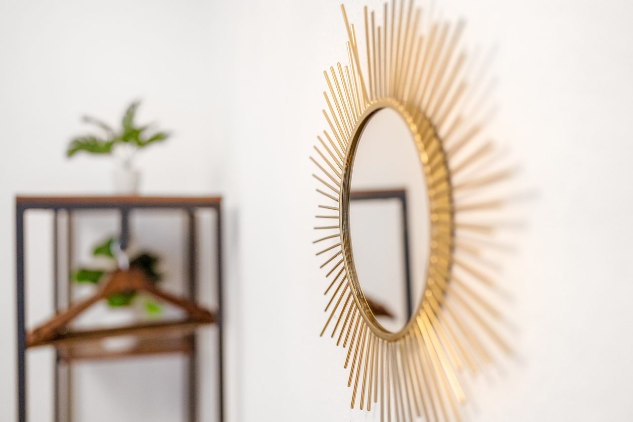 Goldener Sonnenspiegel an der Wand neben einem Kleiderregal