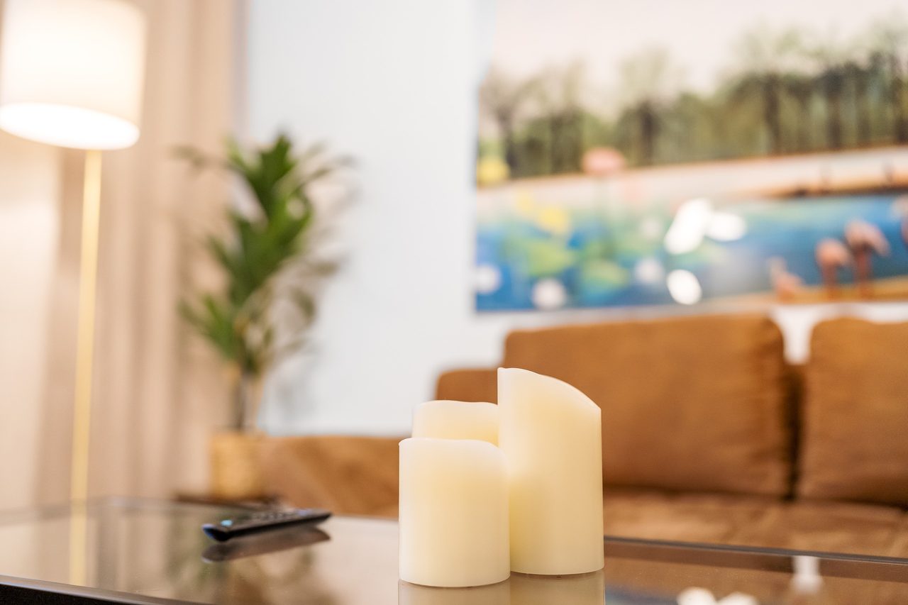 Wohnzimmer mit Kerzen auf dem Couchtisch und braunem Sofa im Hintergrund