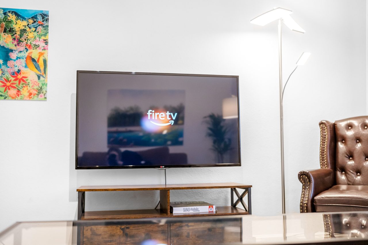 Wohnzimmer mit Wandfernseher, Holzlowboard und Ledersessel