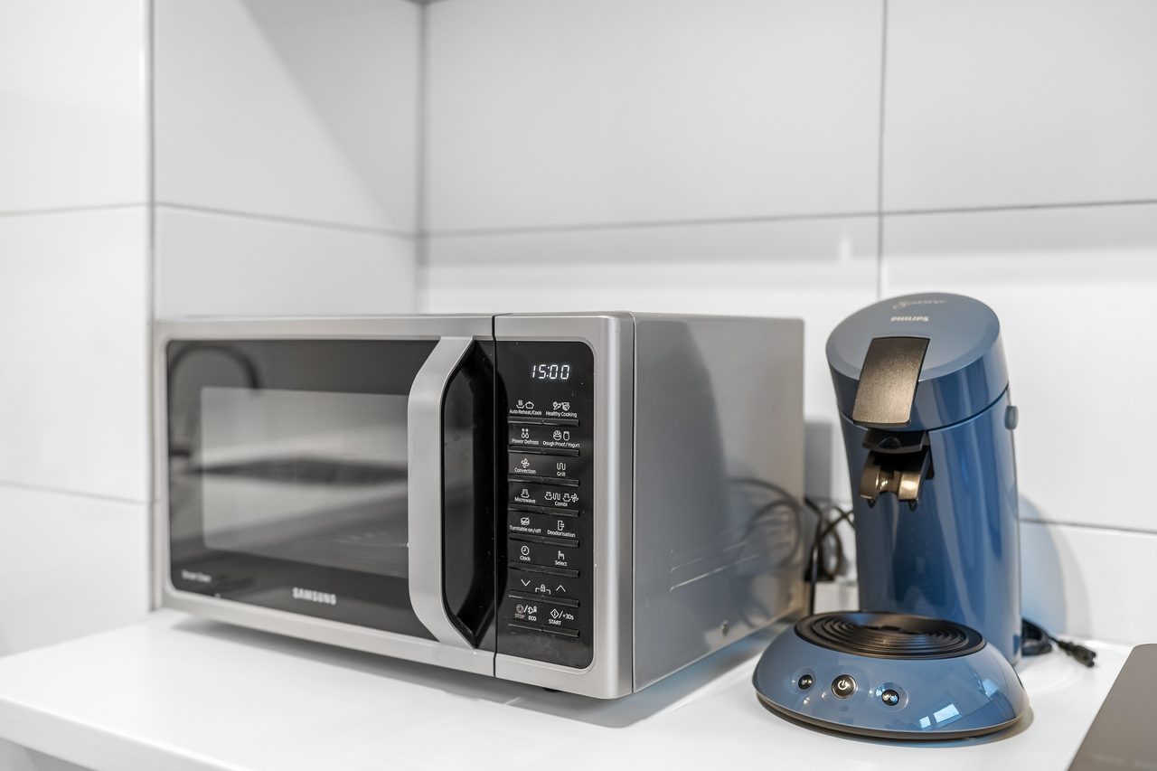 Mikrowelle und Kaffeepadmaschine auf weißer Arbeitsplatte