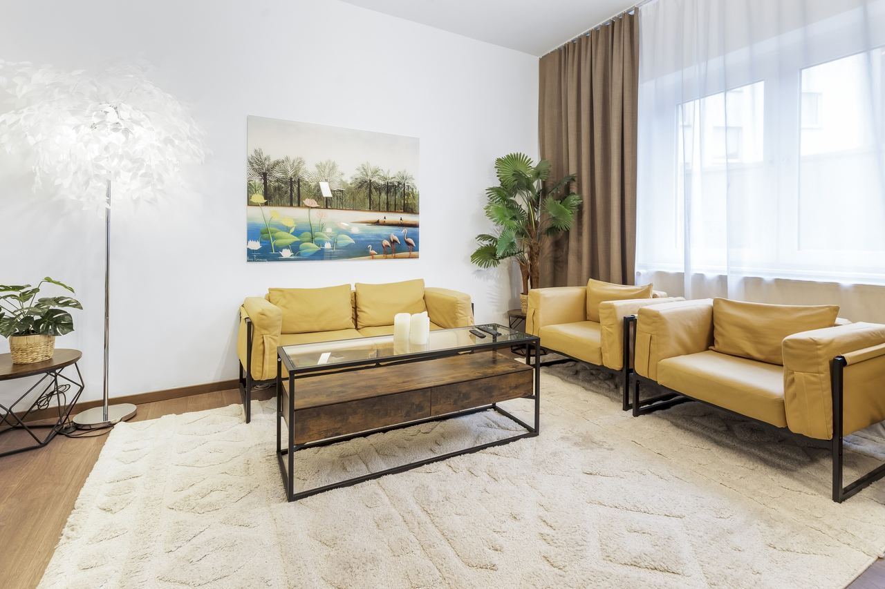 Wohnzimmer mit gelben Ledersesseln, Glascouchtisch und Wandbild