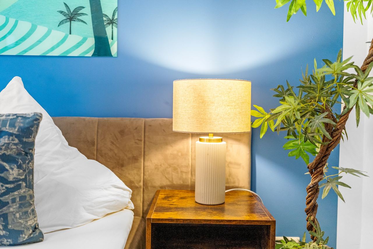 Nachttisch mit Lampe neben Bett an blauer Wand