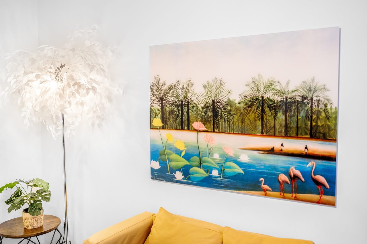 Wandbild mit Palmen und Flamingos über gelbem Sofa