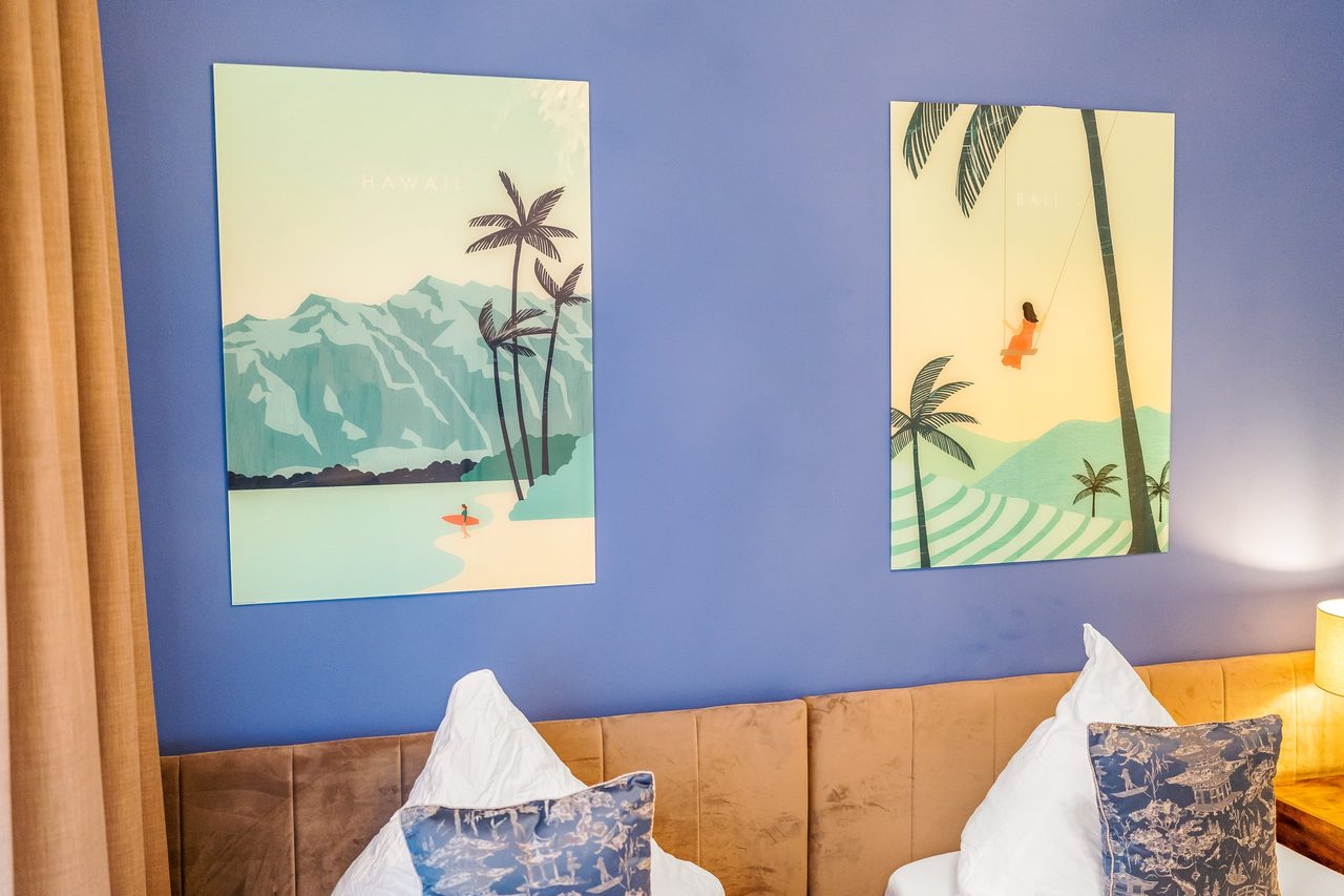 Palmenbilder an blauer Wand über zwei Betten