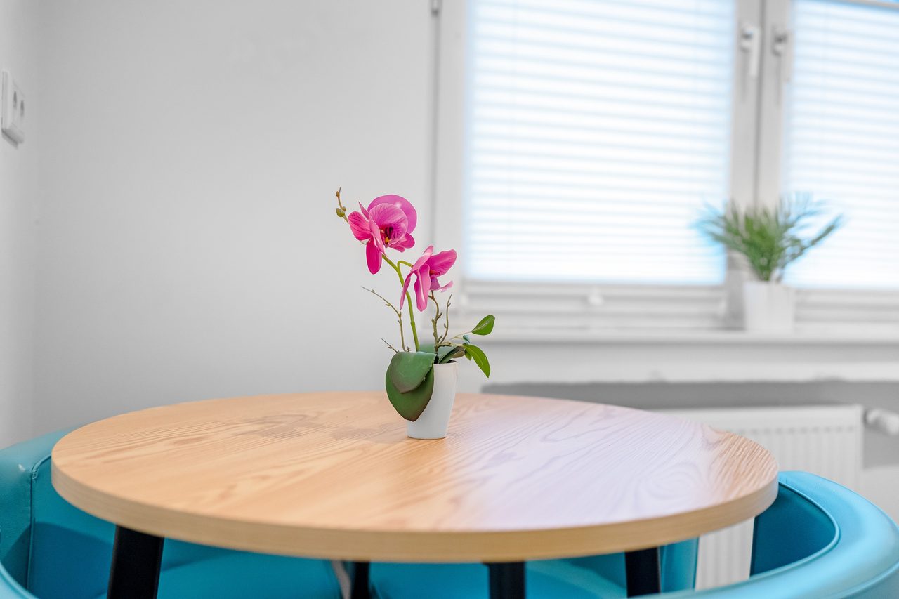 Runder Holztisch mit Orchidee vor dem Fenster