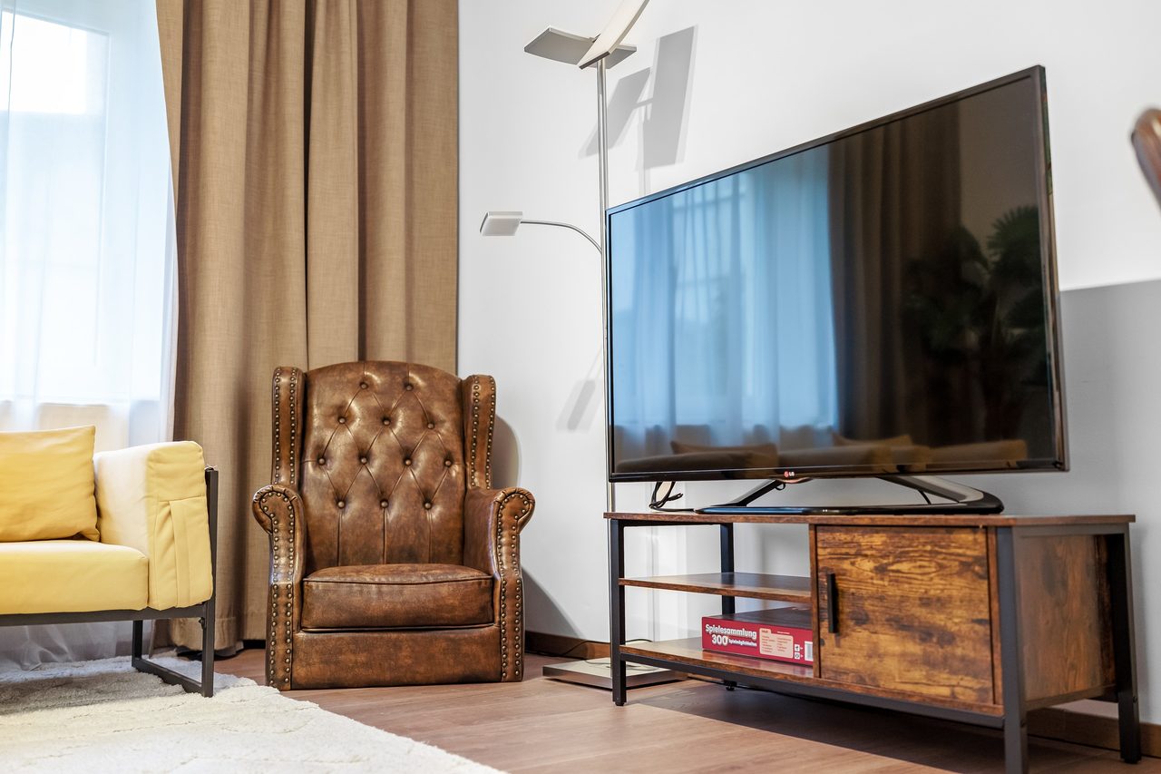 Wohnzimmer mit Ledersessel, großem Fernseher und Stehlampe
