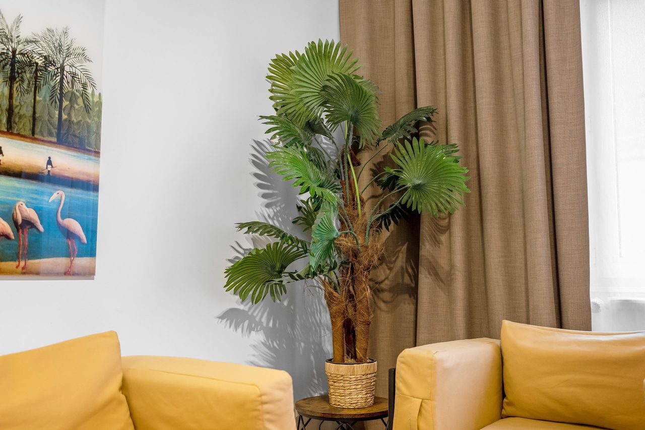 Wohnbereich mit Palme, gelben Sesseln und Flamingobild