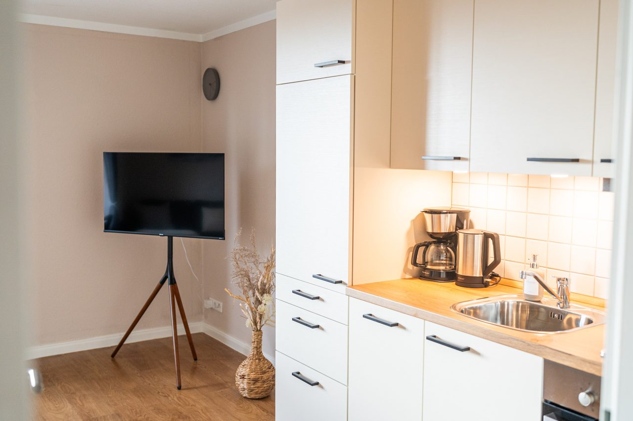 Küchenzeile mit Spüle, Kaffeemaschine und Fernseher auf Ständer
