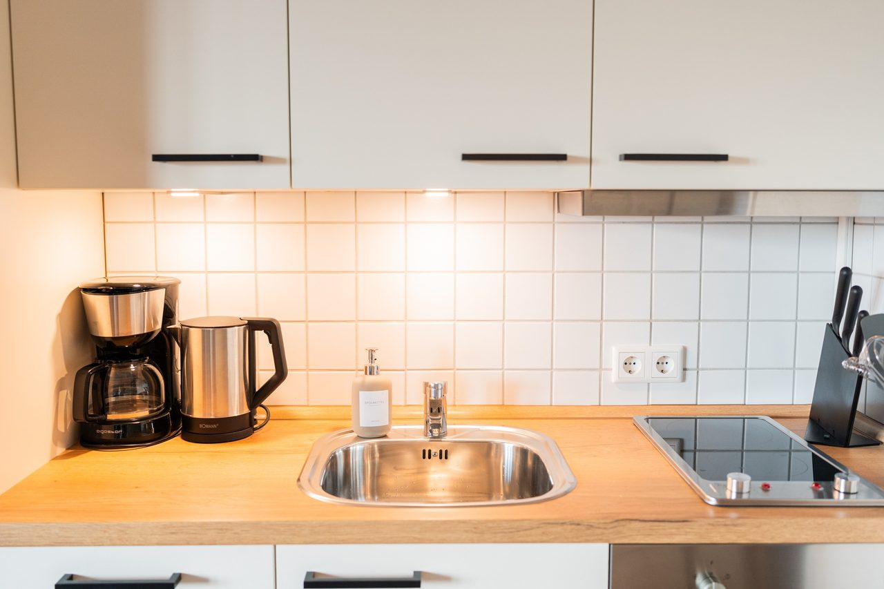 Küchenzeile mit Spüle, Kaffeemaschine, Wasserkocher und Kochfeld