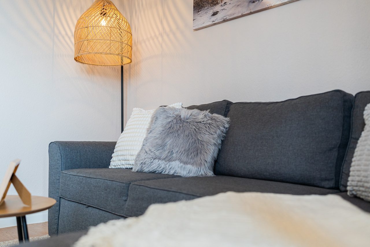 Blaues Sofa mit Fellkissen und Stehlampe aus Rattan