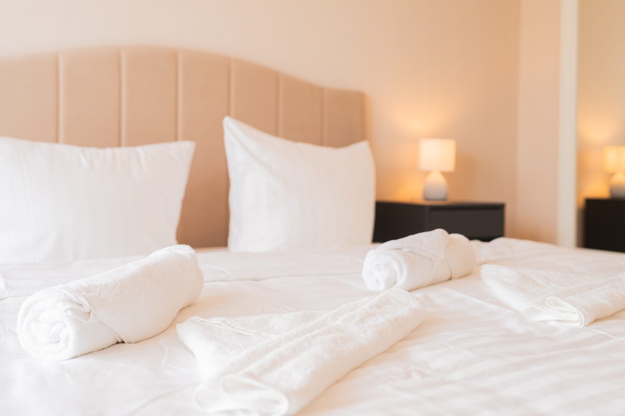 Doppelbett mit gerollten Handtüchern und Nachttischlampe