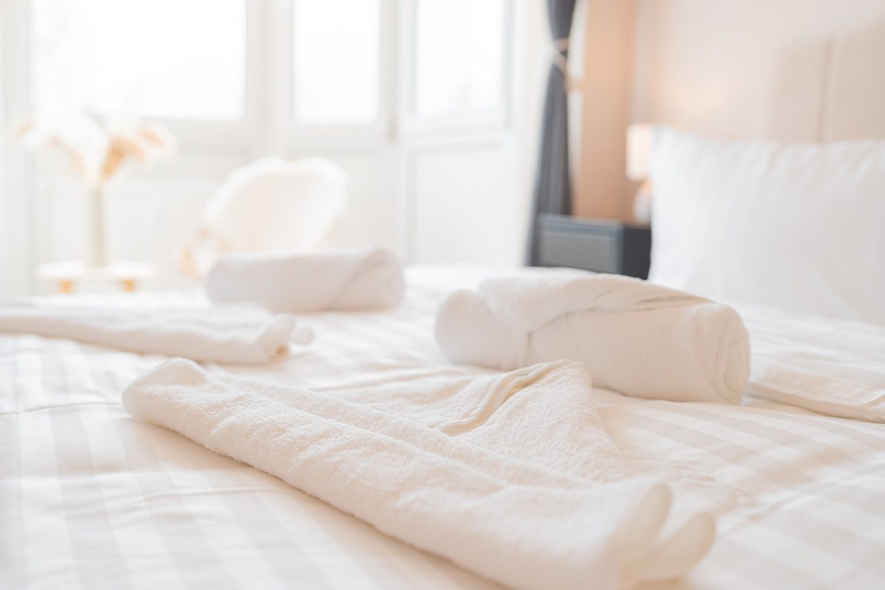 Bett mit gerollten Handtüchern vor hellen Fenstern