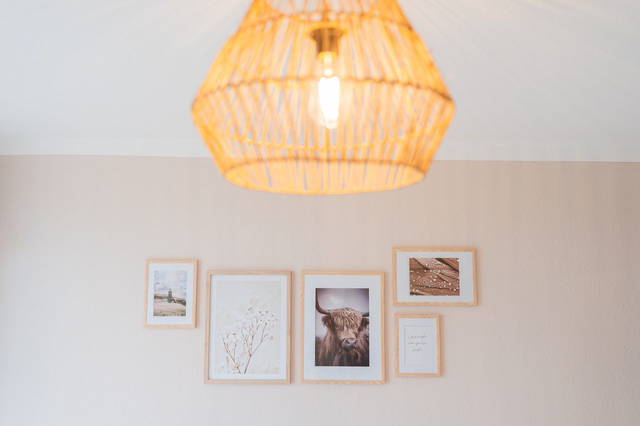 Pendelleuchte aus Rattan und Bildercollage an heller Wand