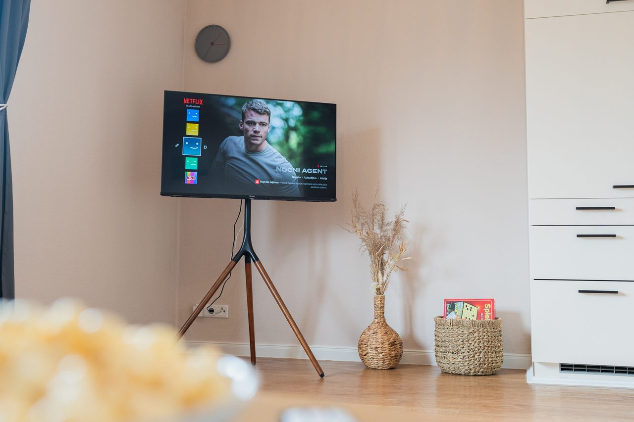 Fernseher auf Dreibeinständer, davor unscharf eine Schüssel Popcorn