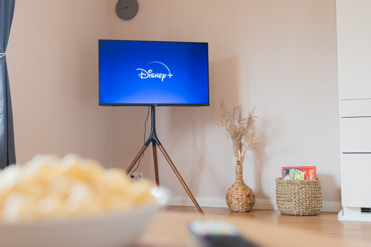 Fernseher mit Disney Plus auf Ständer, Popcorn im Vordergrund
