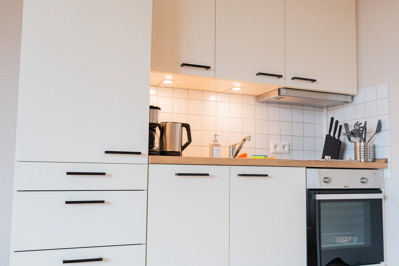 Weiße Küchenzeile mit Backofen, Wasserkocher und Messerblock
