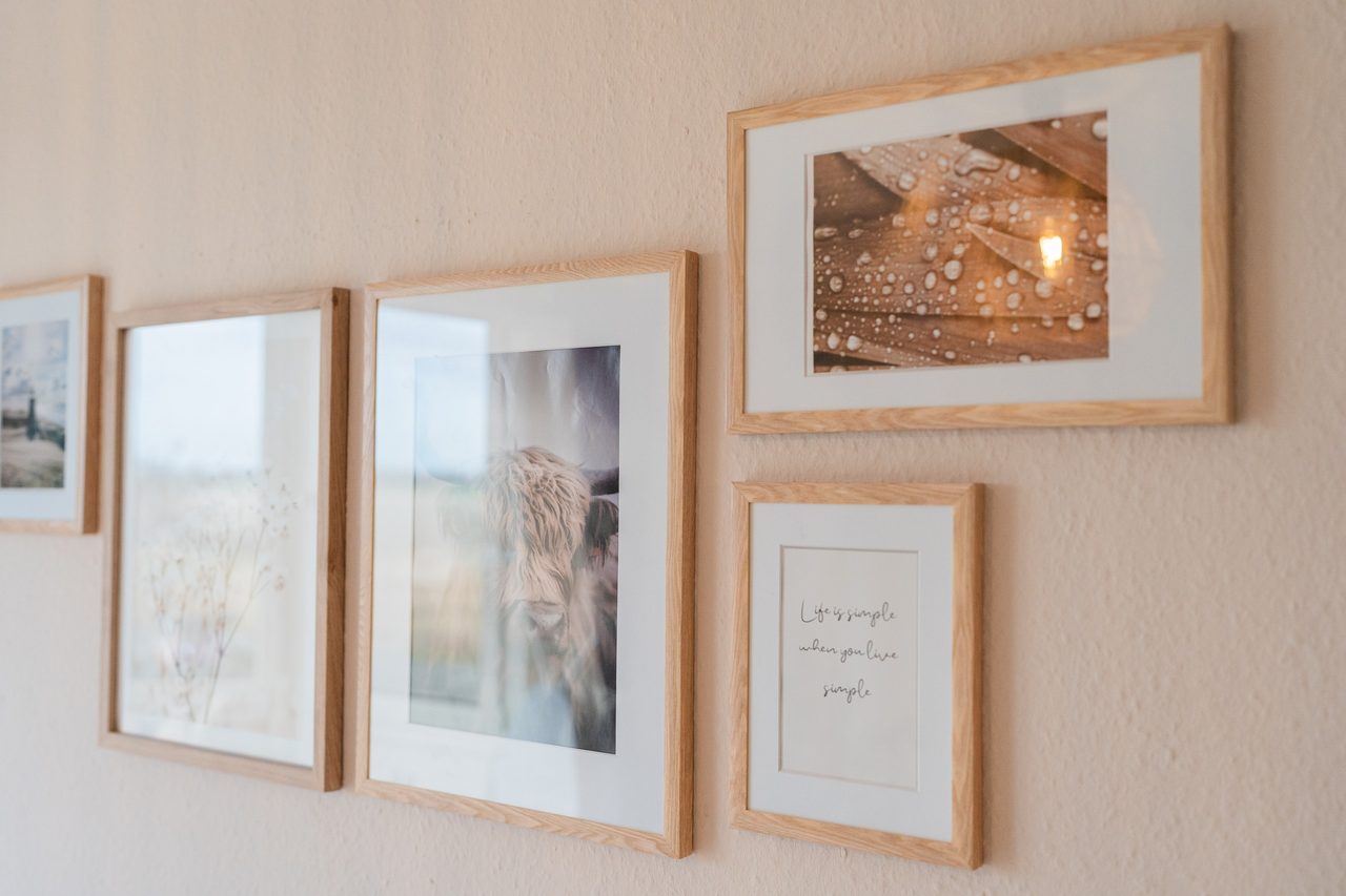 Bilderrahmen mit Fotos und Schriftzug an heller Wand