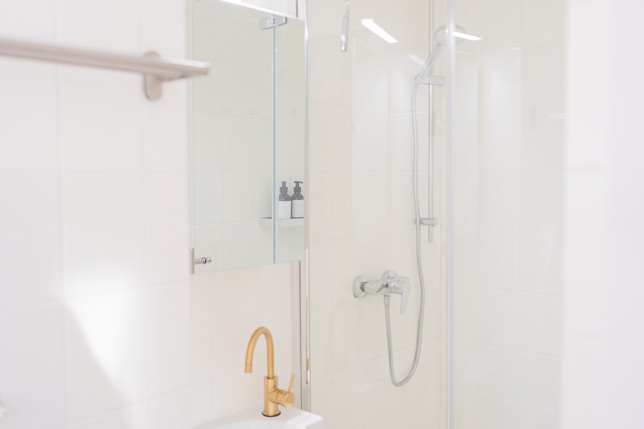 Badezimmer mit Dusche, Glaswand und goldener Armatur