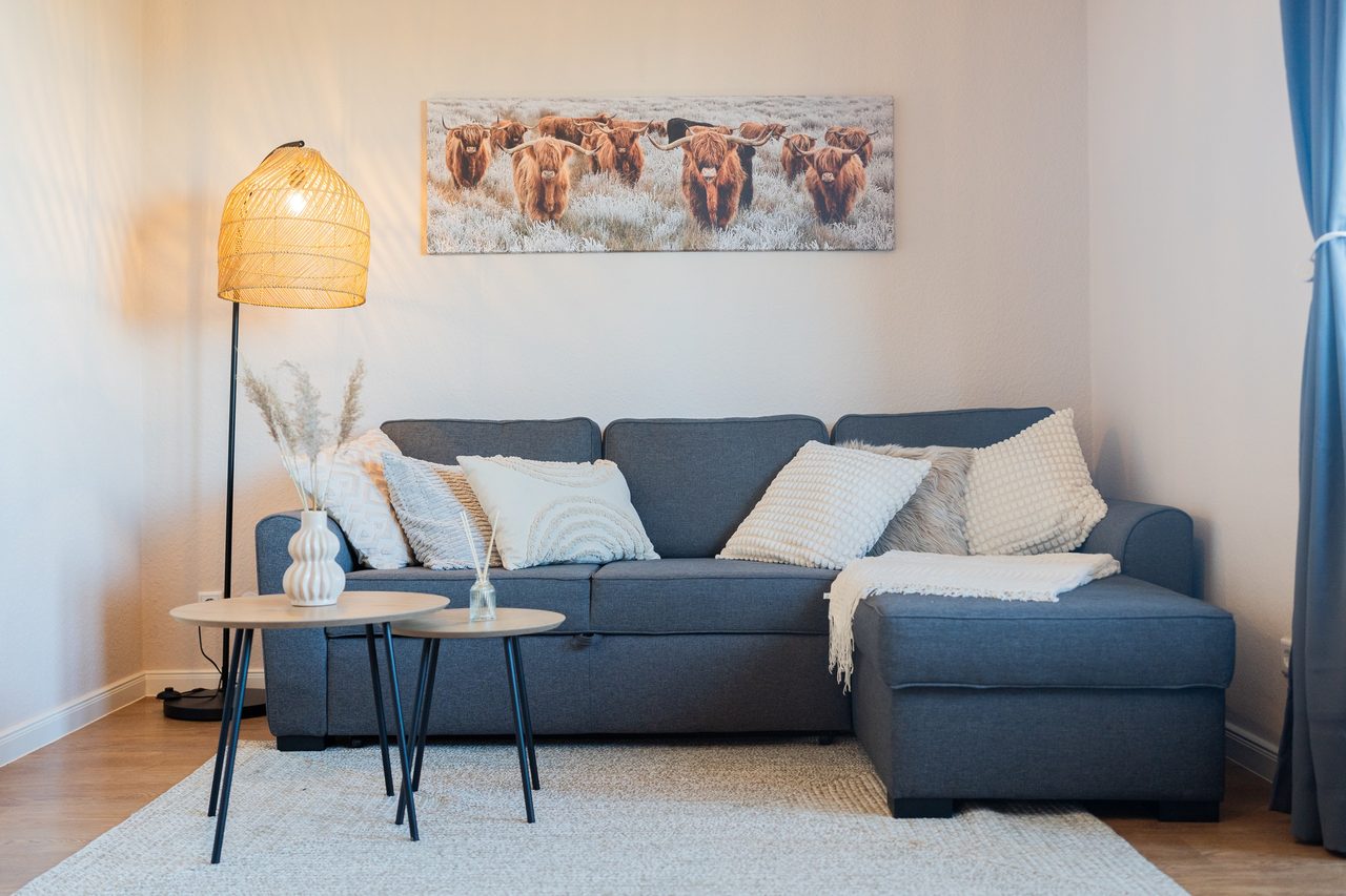 Graues Ecksofa mit Kissen, Beistelltischen und Rattan-Stehlampe