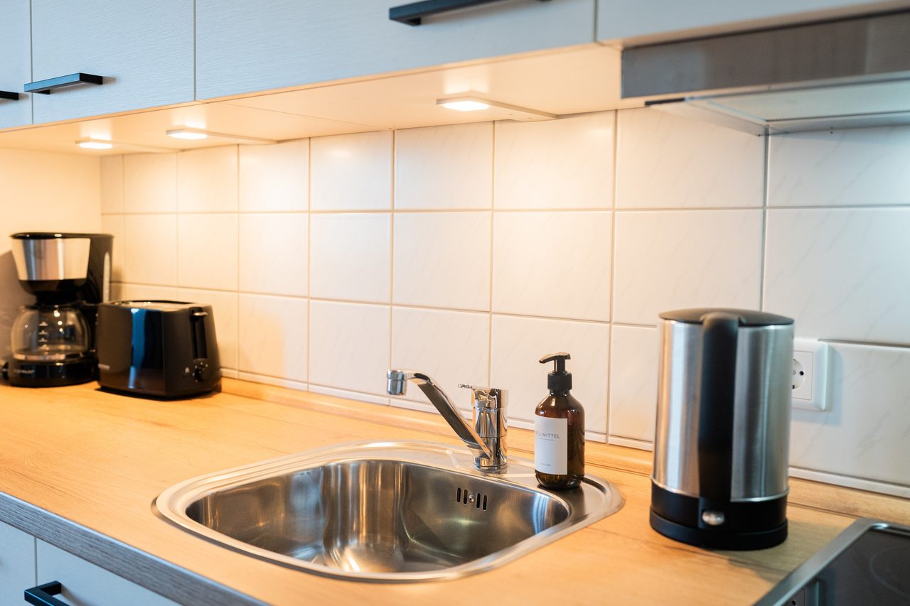 Küchenzeile mit Spüle, Kaffeemaschine, Toaster und Wasserkocher