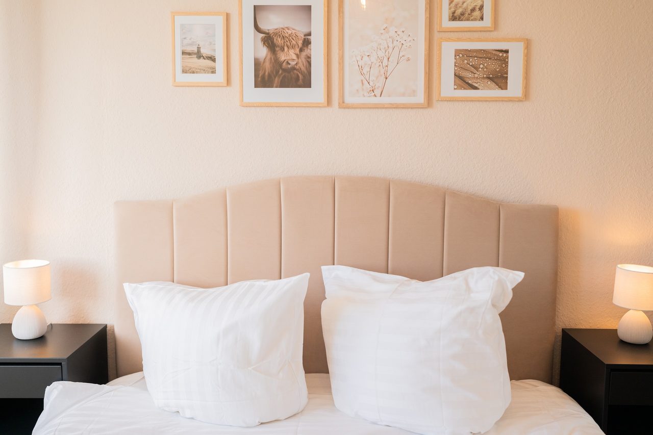 Doppelbett mit Polsterkopfteil, weißen Kissen und zwei Nachttischlampen