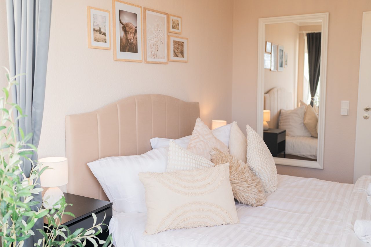 Schlafzimmer mit Doppelbett, Standspiegel und Bilderwand