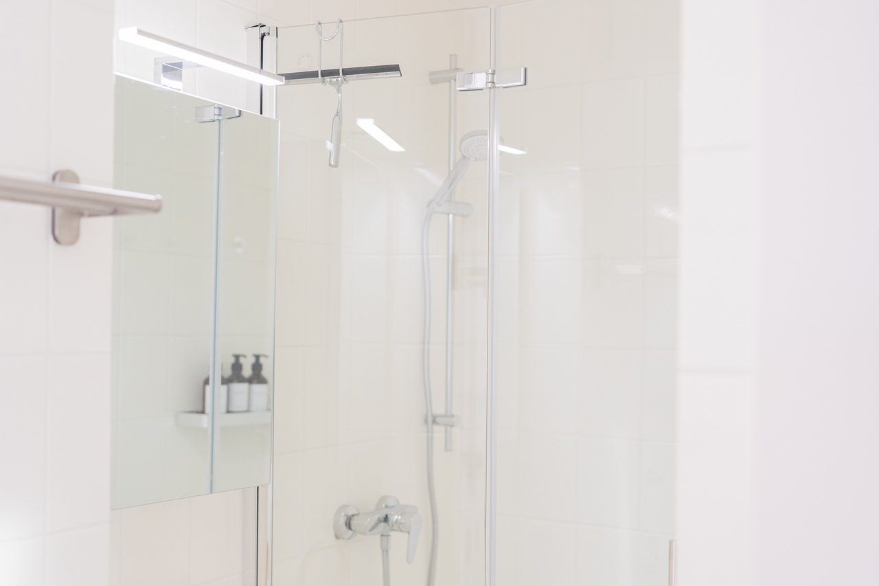 Badezimmer mit Dusche, Glaswand und weißen Fliesen