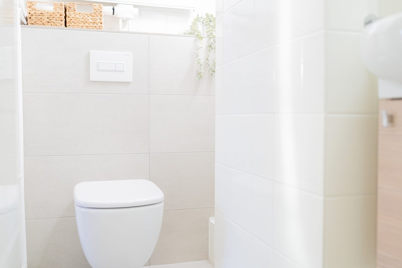 Badezimmer mit Wand-WC und weißen Fliesen