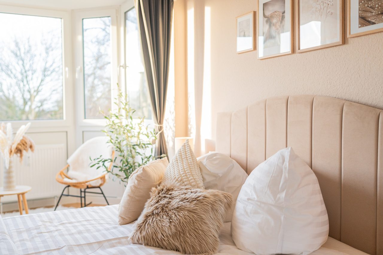 Schlafzimmer mit Doppelbett, Polsterkopfteil und Erker mit Sessel