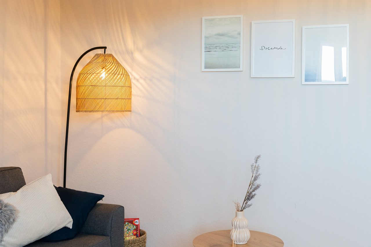 Wohnzimmer mit Stehlampe aus Rattan, Sofa und Bildern an der Wand