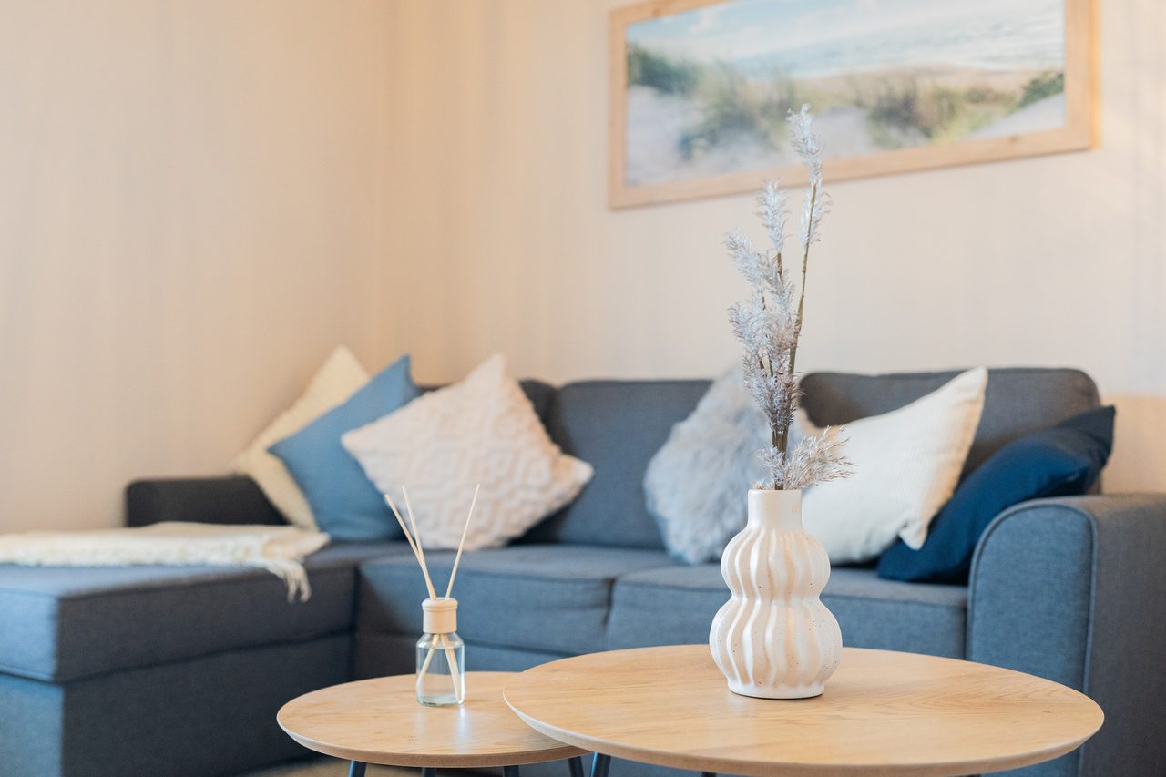 Blaues Ecksofa mit Kissen und zwei runden Beistelltischen