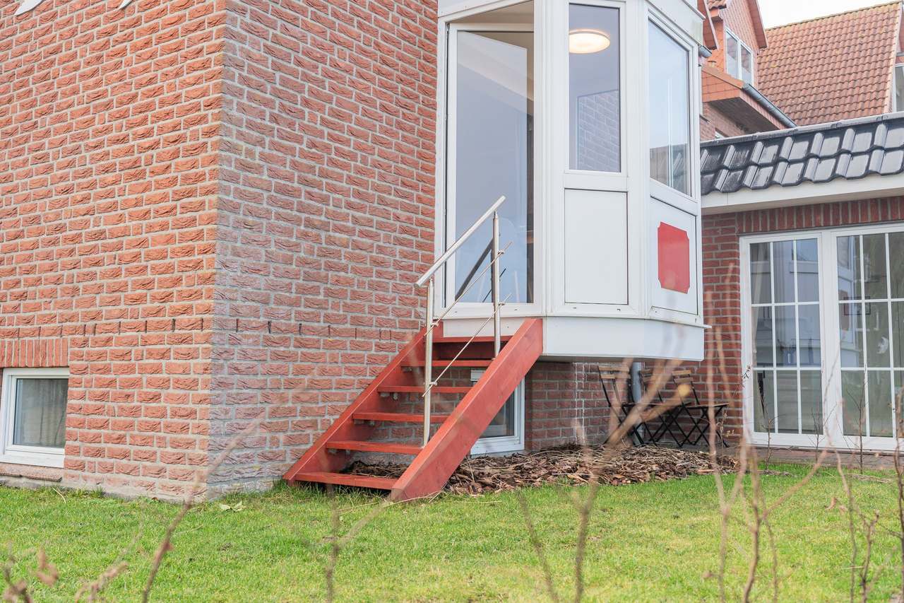 Backsteinhaus mit roter Außentreppe und Rasen