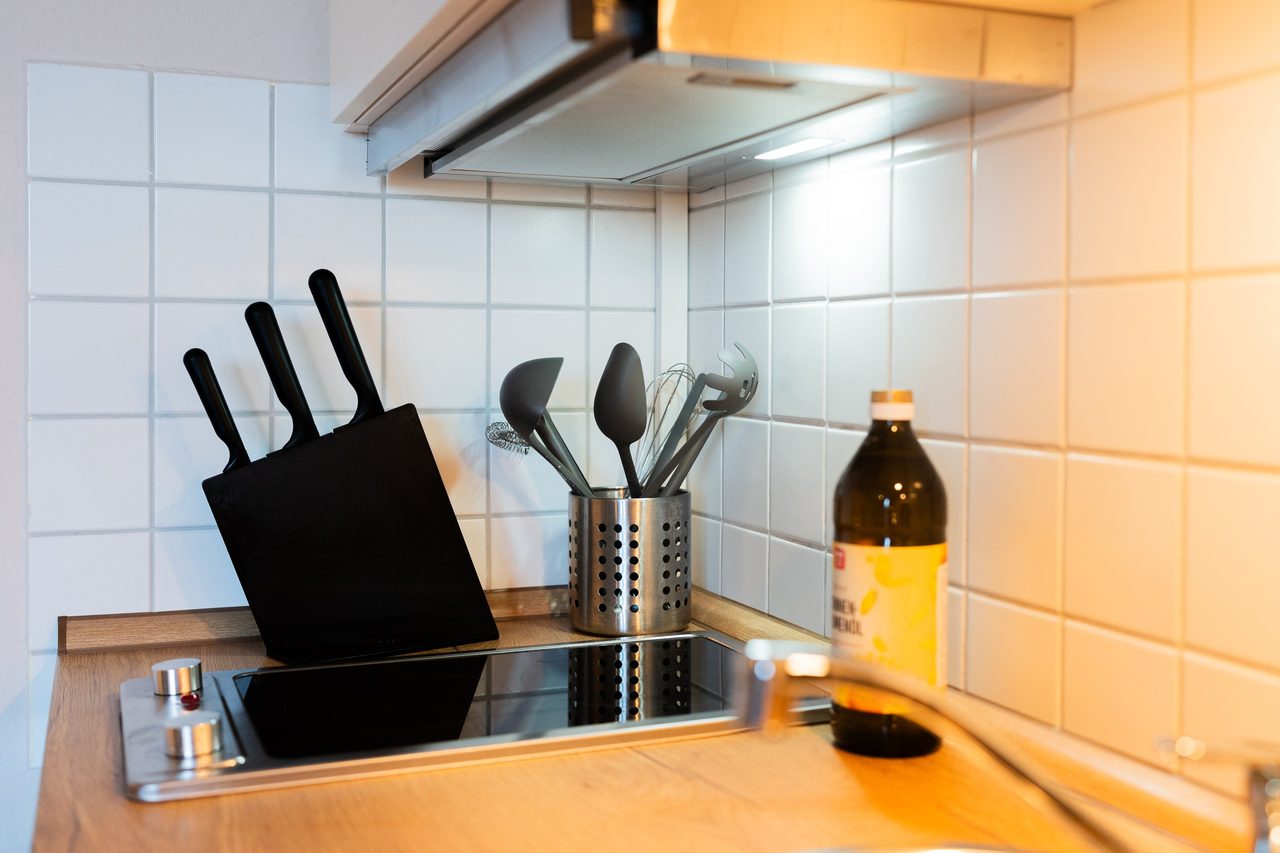 Kochfeld mit Messerblock, Küchenhelfern und Dunstabzug