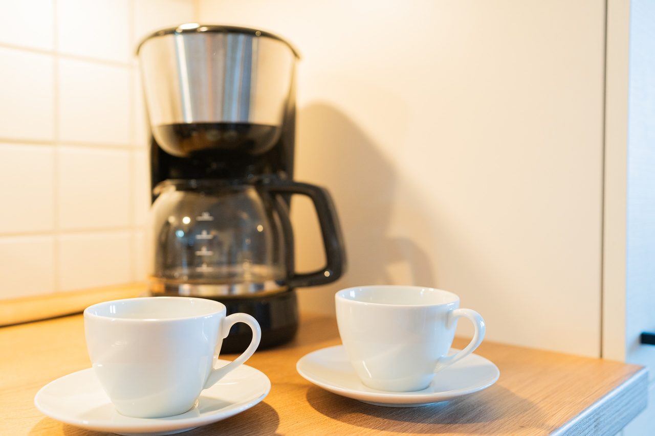 Kaffeemaschine und zwei weiße Tassen auf der Arbeitsplatte